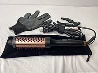 Curling iron brush with heat-resistant glove, hair clips, and storage pouch on a white surface.