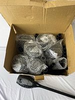Open box showing multiple LED solar torch lights individually wrapped in bubble wrap with long stakes visible.
