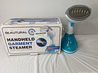 Front view of the steamer with box, showing the product and packaging with branding and features.