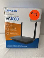 Front of Linksys AC1000 router box showing dual-band Wi-Fi 5 router with two antennas and product branding.