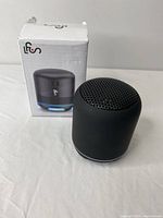 Mini portable wireless Bluetooth speaker with original packaging box, front view.