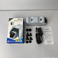 Full lot layout showing charging dock, power adapter, thumb grips, user manual and retail box