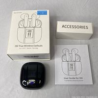 Photo showing the Renimer I50 earbuds packaging box with price sticker, black glossy charging case, white accessories box, and user guide pamphlet.