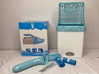 Photo showing the full set of items on a surface: blue cat litter shovel with built-in holder, white and blue litter box, and two blue rolls plus plastic component.