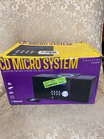 Photo of the Proscan CD Micro System box showing product image, purple and yellow packaging, and branding.