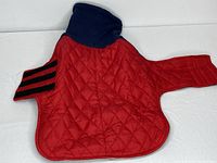 Red quilted dog coat with navy blue hood laid flat showing the exterior.