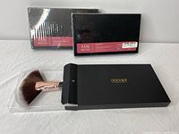Set of three boxed fan makeup brushes by Docolor with one brush shown out of box on white background.