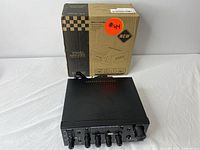 Stereo amplifier KS-338T with original box behind it, black metal casing, power cord visible on the top