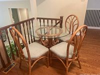 Top front angle showing the full table and three matching rattan chairs with light gray seat cushions.