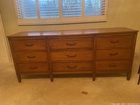 Frontal view of the solid wood dresser showing nine drawers and metal handles.