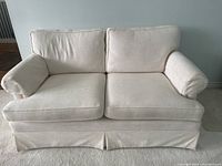 Front view of white two-seater fabric love seat showing cushions and armrests.