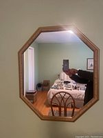 Full view of hexagon shaped mirror mounted on wall showing room reflection