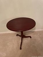 Oval mahogany side table with pedestal legs, showing the table surface and leg detail.
