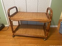 Front view of the rattan table showing two shelves and wheels