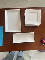Top view of three plates showing a rectangular platter, a smaller rectangular plate, and stacked square dessert plates.
