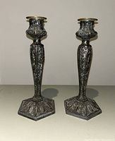 Pair of silver plated Rogers candlesticks showing front view with detailed floral pattern and hexagonal base