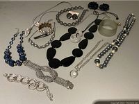 Photo showing multiple pieces of black, silver, and blue costume jewelry including necklaces, bracelets, earrings, and vintage shoe clips.