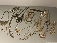 Full view of the lot with all necklaces, bracelets, and hat pins arranged on a table.