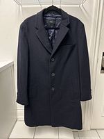 Front full-length view of navy blue men's overcoat hanging on a hanger.