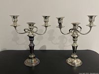 Pair of vintage silver plated double candle holders with tarnished and polished areas, shown from front.