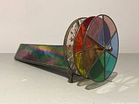 Close-up angle of kaleidoscope showing colorful stained glass discs and iridescent body.