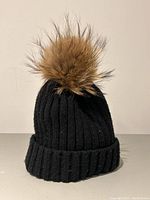 Front and side view of the black ribbed knit toque with brown coyote fur pom pom against a plain background