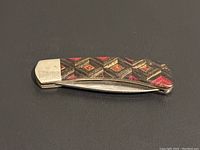 Closed view of vintage pocket knife showing decorative handle with diamond pattern and metal end cap.