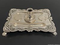 Top view of the vintage silver plated footed inkwell stand showcasing flower-patterned edges and central pen holder with two circular inkwell spaces.