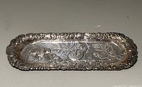 Front view of silver plated elongated dish with embossed bird and floral design, showing overall condition and details.