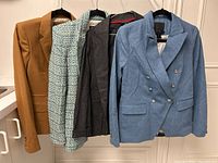 Four women’s blazers on hangers showing colors and styles: camel J Crew, green tweed, dark charcoal, blue double-breasted.