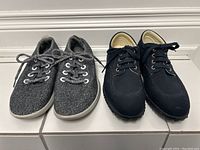 Pair of Allbirds grey wool running shoes size 8 and Hogan black canvas shoes size 9 shown side by side from above on tiled floor.