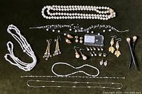 Photo showing pearl necklaces including long cultured pearl strands, black cord necklace with pearls, various pearl stud earrings and dangling earrings, and a string of loose pearls or small beads.
