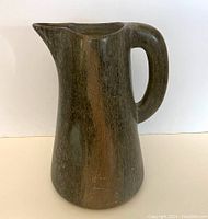 Front angled view of polished hardstone pitcher, showing spout and handle with natural striations and good condition.
