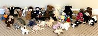 Photo of a large assortment of plush toys including Beanie Babies featuring various animals sitting on the floor against a wall