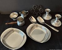 Photo showing all pewter and stainless steel items including candle holders, sugar/creamer, salad fork and spoon, trivet, and brandy pourer.