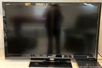 Front view of 42-inch Sharp Aquos TV, screen and bezel visible with stand.