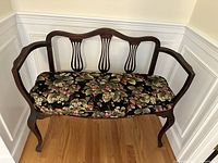 Front view of loveseat showing dark mahogany frame, cabriole legs, wide curved armrests, three harp slats on backrest, and floral cushion on seat