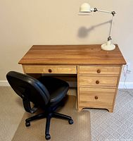 Maple desk with four drawers, office chair, and desk lamp, showing overall setup and condition
