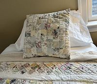 Close-up of patchwork throw pillow and quilt in muted colors