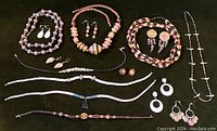 Full view of assorted natural material necklaces and earrings arranged on black background