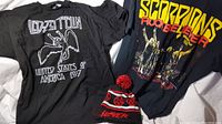 Two black T-shirts with rock band designs, and one Slayer branded snow hat