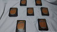 Six piles of Magic The Gathering cards arranged on a white surface, showing card backs clearly.