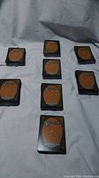 Eight stacks of Magic The Gathering cards arranged on a white cloth, showing the back card design and protective sleeves.