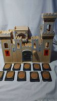 Front view of the wooden medieval castle with 10 decks of sleeved Magic The Gathering cards arranged in front.