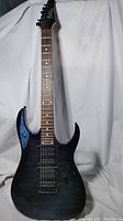 Full length view of Ibanez Gio GRX70QA guitar front showing black sunburst color and neck.