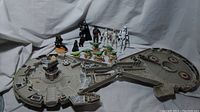 Wide view showing the foldable Micro Machines Millennium Falcon playset with all included Star Wars miniature characters arranged behind it.