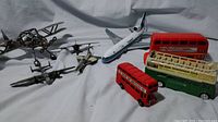 Wide shot of various diecast metal airplanes and British double decker buses arranged on a white background.