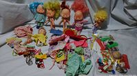 Full view of 3 Strawberry Shortcake dolls and many assorted clothes and accessories laid out on white surface.