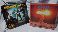 Two vinyl records shown side by side. Left: Sir Mix-A-Lot Special Double cover with group photo under moody lighting. Right: Count Basie album cover with nuclear explosion artwork.