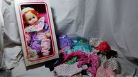 Full lot photo showing vintage clown baby doll in original box and multiple colorful clown-themed doll clothes laid out